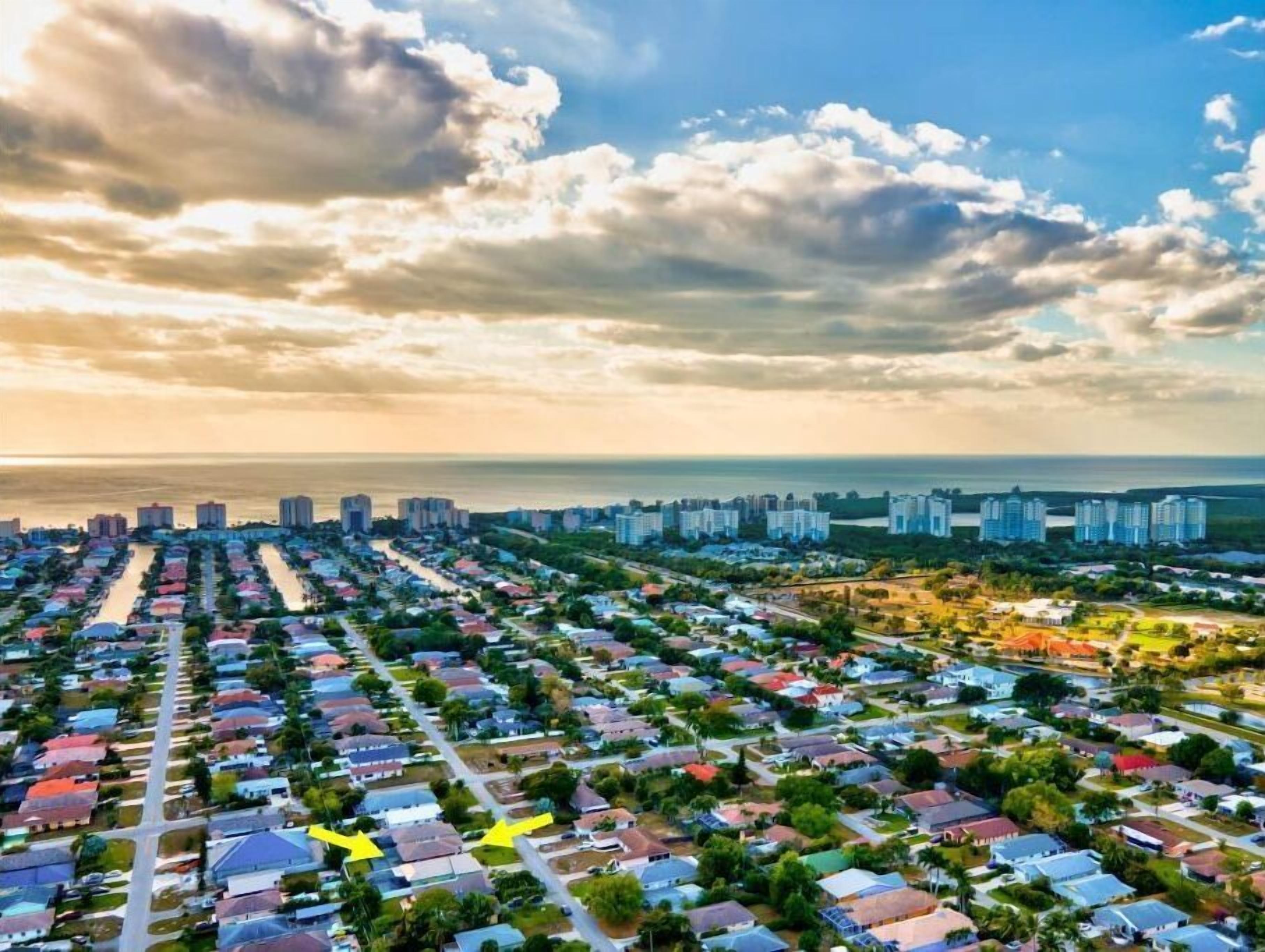 A residential area with a mix of single-family homes and apartment buildings, a clear view of the ocean, and a cloudy sky.