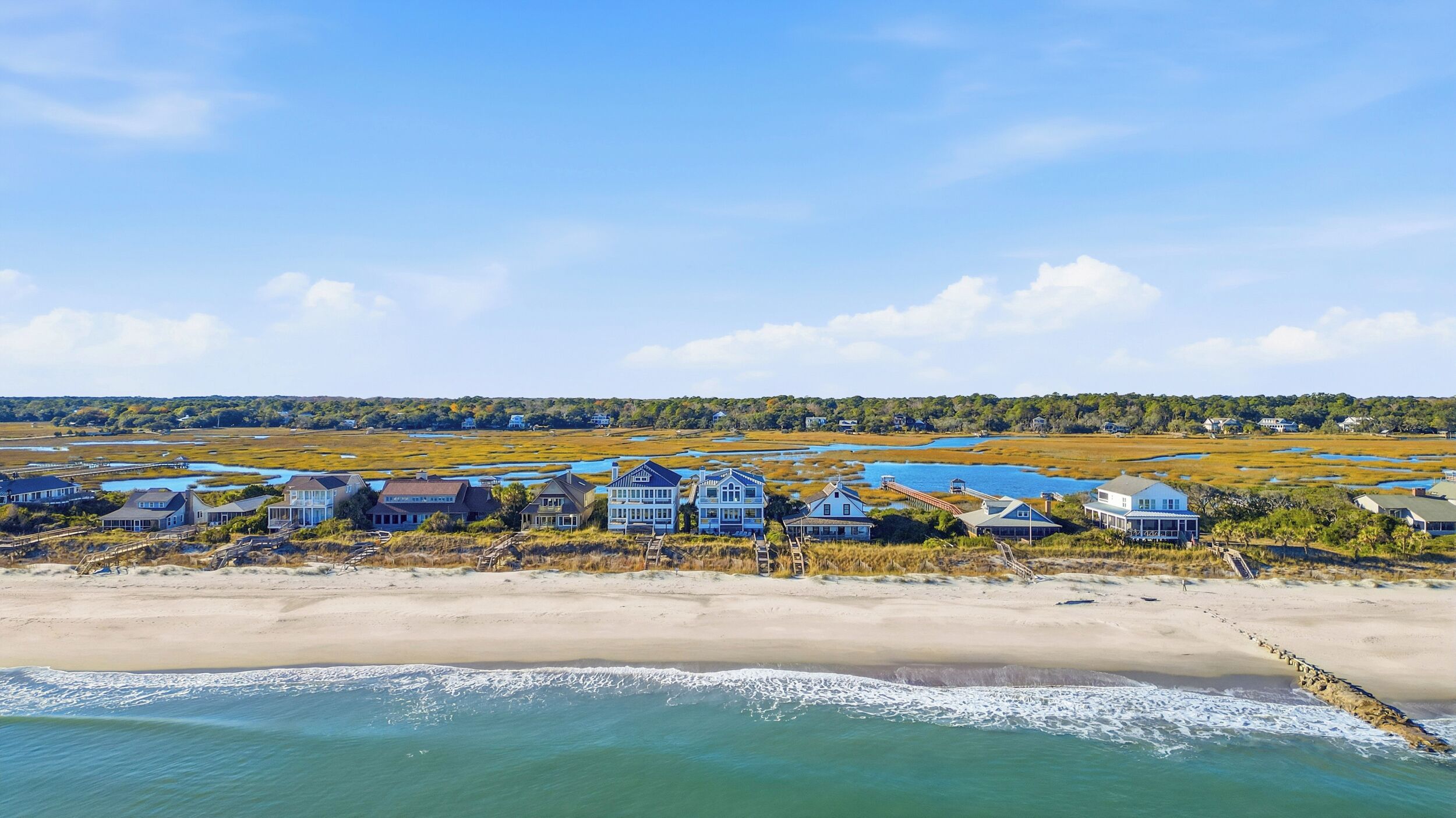 Une propriété située sur la côte, avec des maisons donnant sur la plage, une jetée et un paysage marécageux.