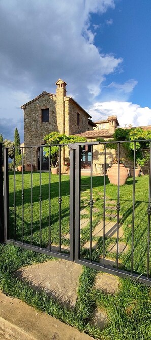 A stone house with a garden and a metal fence. - Passiontoscane : house with private pool, breathtaking view and total confort (San Giovanni d'Asso)