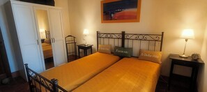 Una habitación de hotel con una cama, dos mesitas de noche, una silla, un armario y un cuadro en la pared.