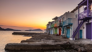 A row of colorful buildings with balconies along a waterfront at sunset. - The Colourful Land Klima, Milos (Klima)