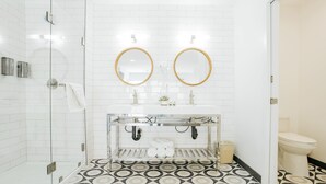 A modern bathroom with a glass shower enclosure, two round mirrors, a white sink with a glass shelf, and patterned floor tiles. - SKS - Superior Room, 1 King Bed with Sofa bed, Non Smoking (Long Beach)