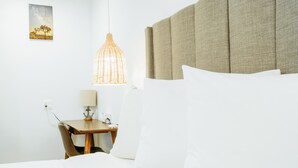 A hotel room with a bed, a nightstand, a lamp, and a hanging light fixture. - DQ -  Deluxe Room, 1 Queen Bed, Non Smoking (Long Beach)