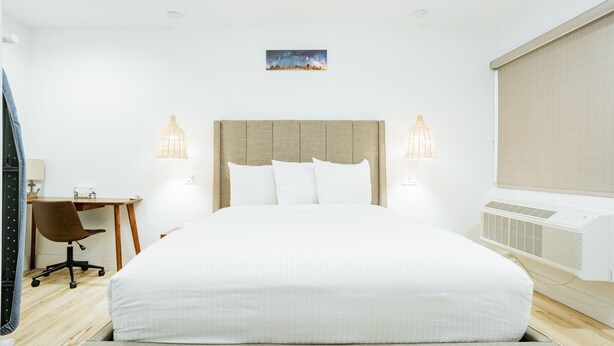 A hotel room with a large bed, two bedside lamps, a desk, and a chair. - DQ -  Deluxe Room, 1 Queen Bed, Non Smoking (Long Beach)