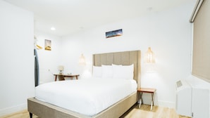 A modern hotel room with a large bed, bedside tables, and a wall-mounted heater. - DQ -  Deluxe Room, 1 Queen Bed, Non Smoking (Long Beach)