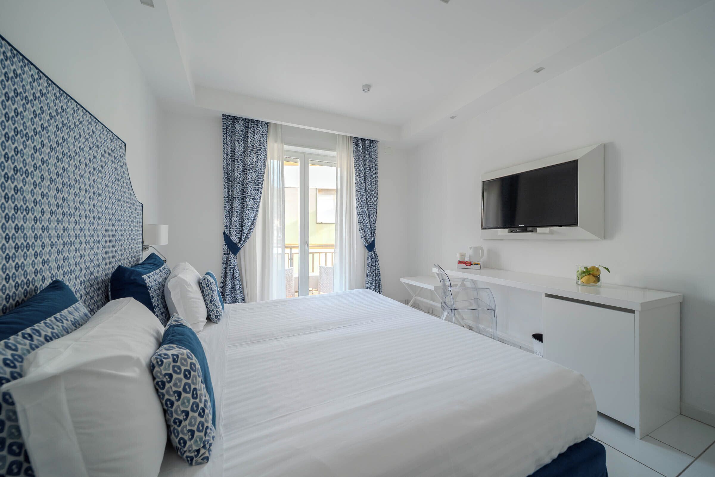 Une chambre d’hôtel moderne, dotée d’un grand lit, d’un bureau et d’une télévision.