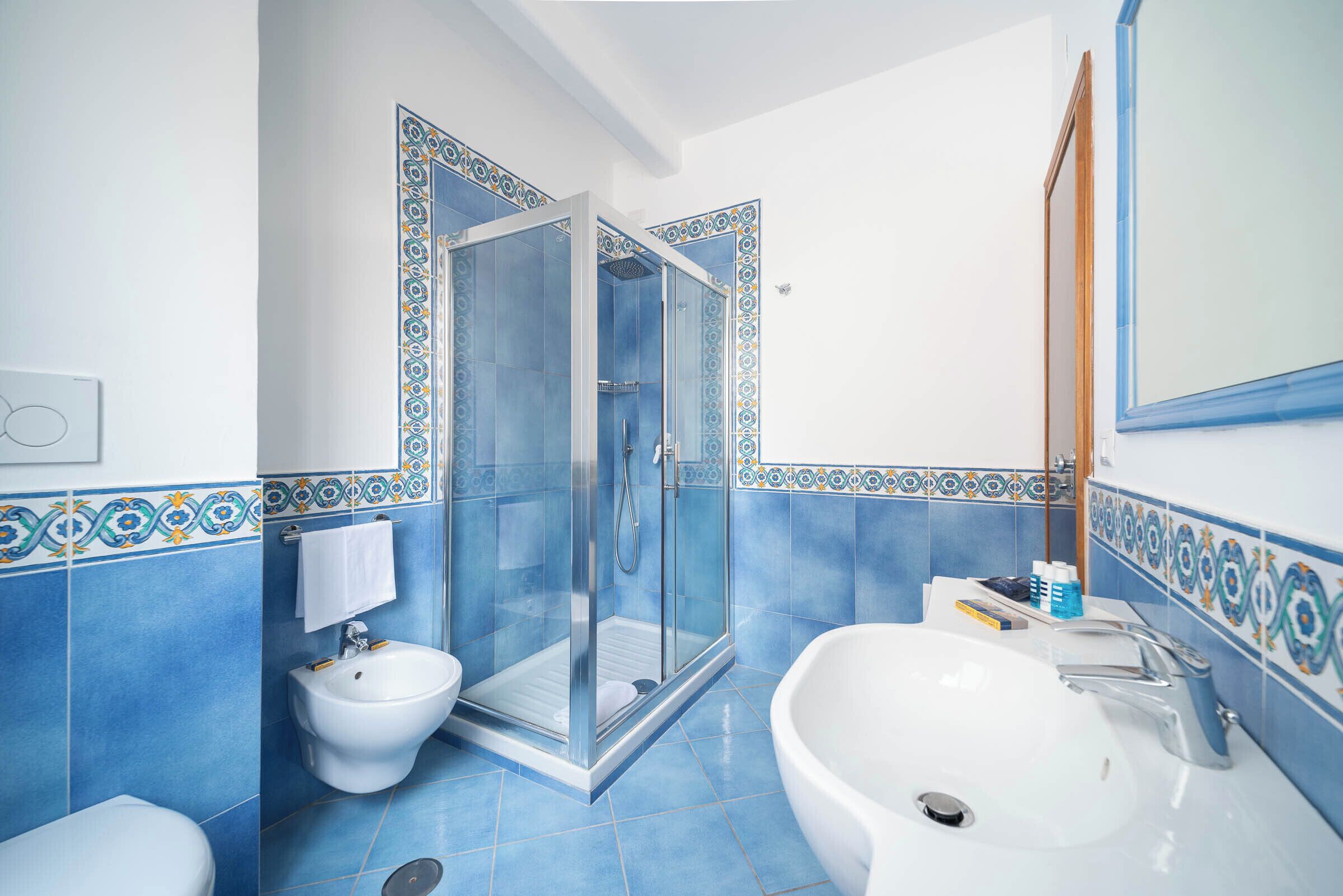 A bathroom with a glass-enclosed shower, a bidet, a sink, and a mirror.