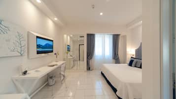Una habitación de hotel moderna con cama, escritorio, silla y televisor montado en la pared.