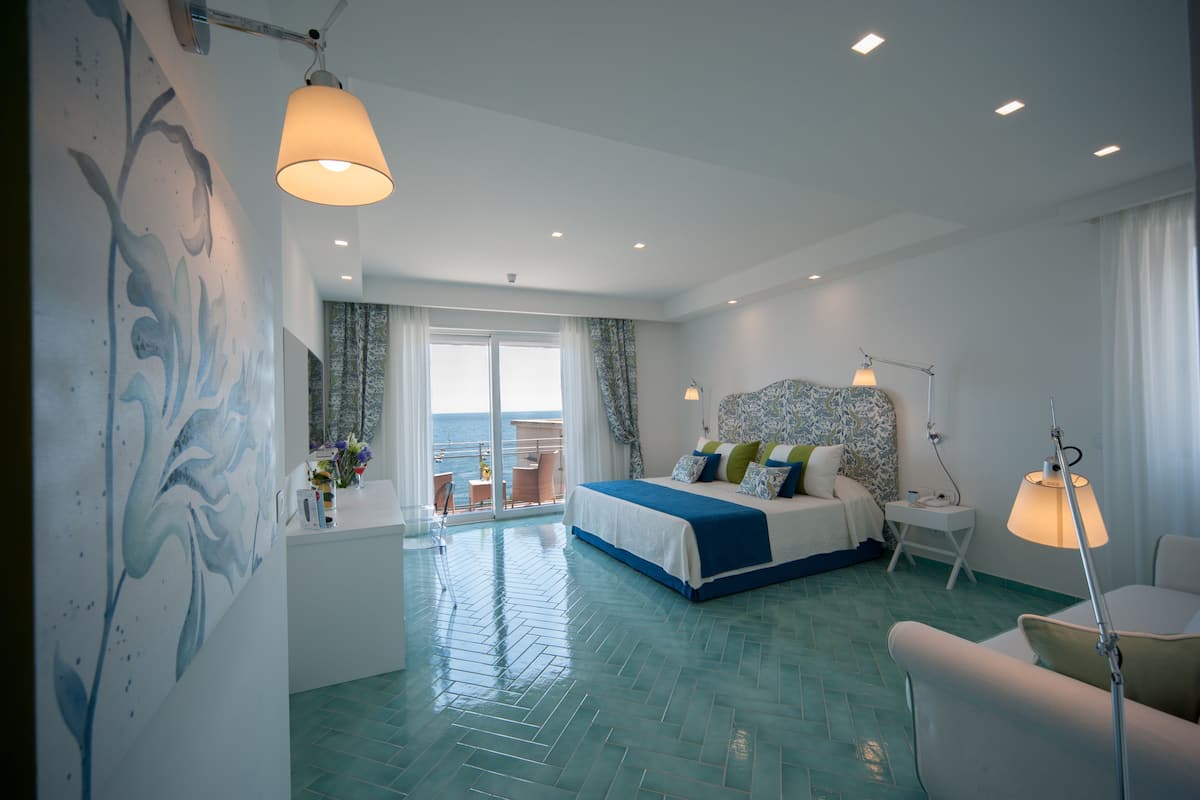 Ein modernes Hotelzimmer mit einem großen Bett, einem Balkon mit Blick und einem dekorativen Wandgemälde.