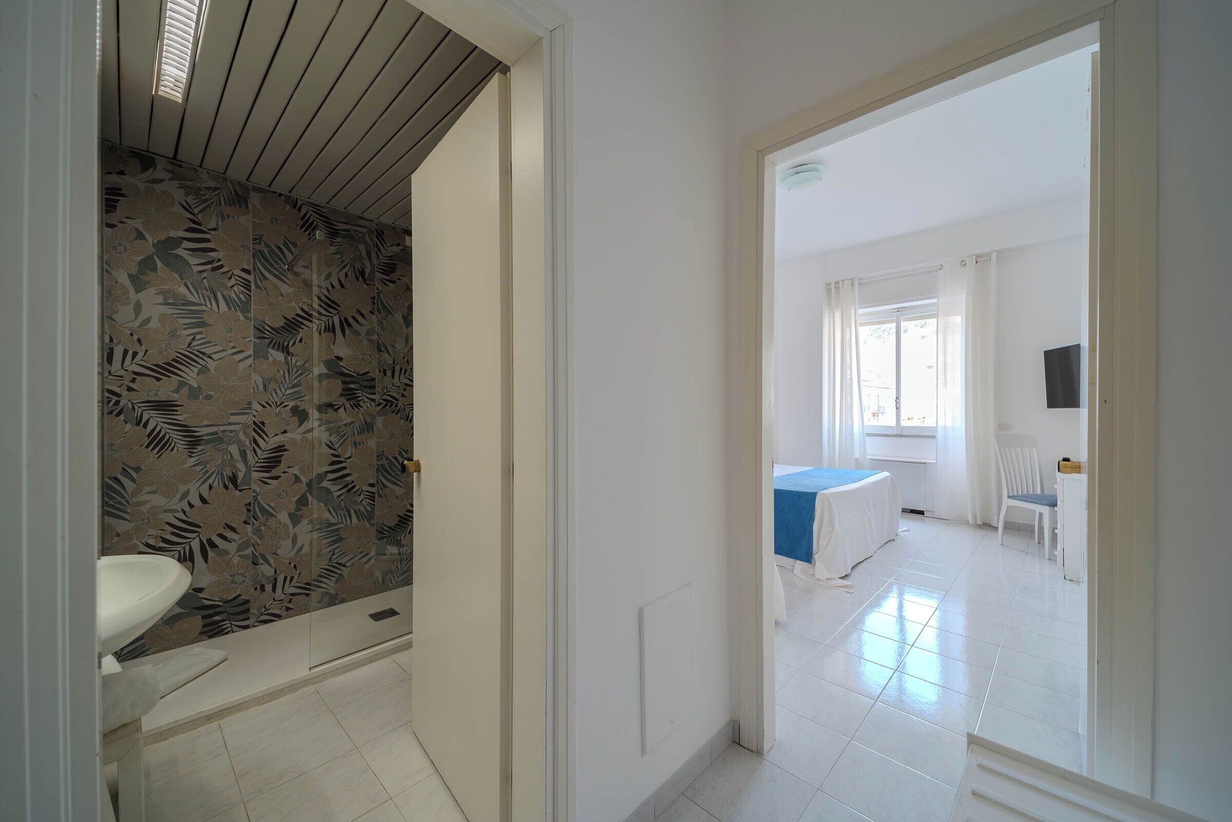 Een badkamer met toilet en wastafel, een slaapkamer met bed en stoel, en een woonruimte met televisie en raam.