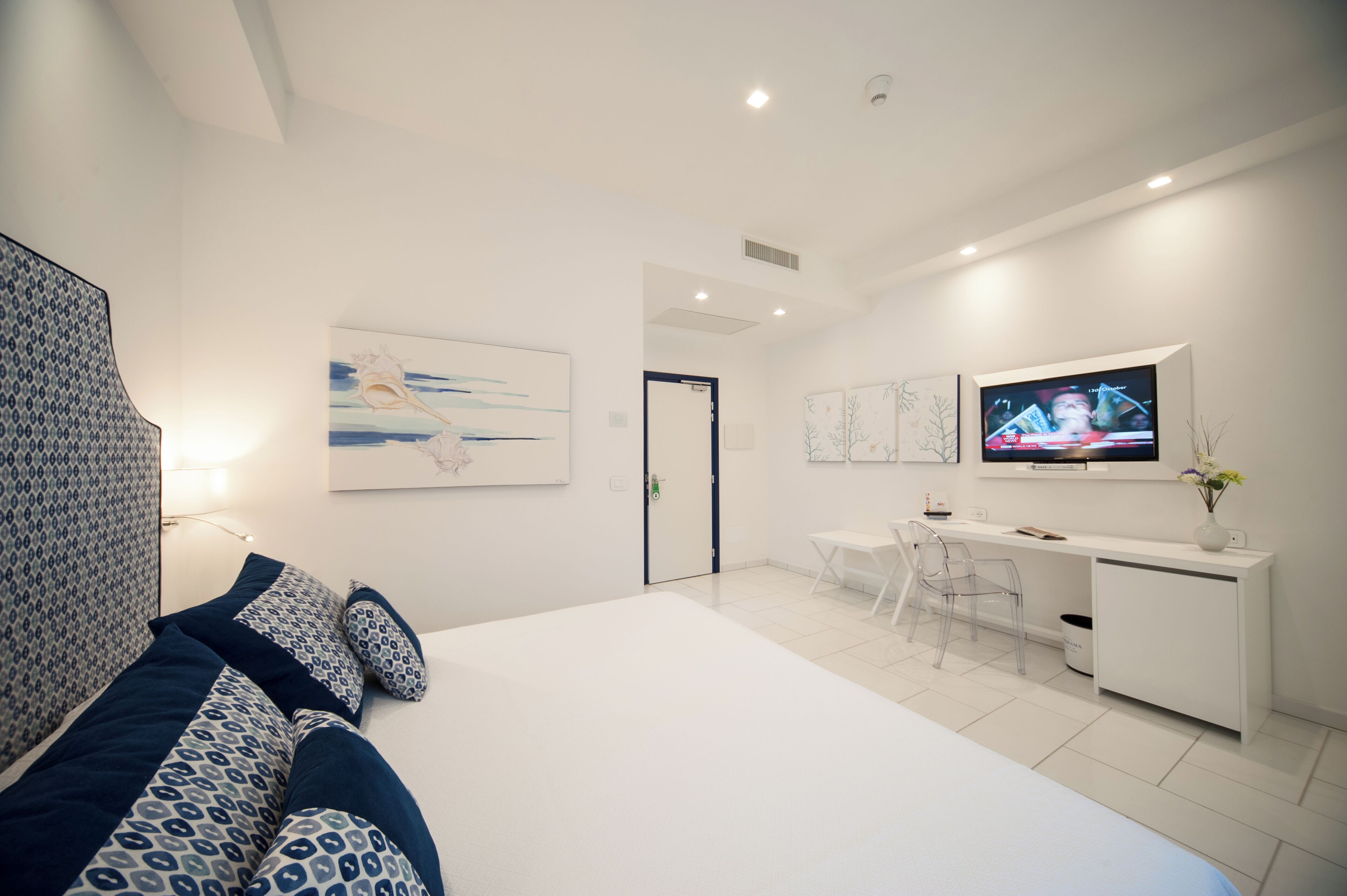 Une chambre moderne avec un grand lit, un bureau et une télévision.