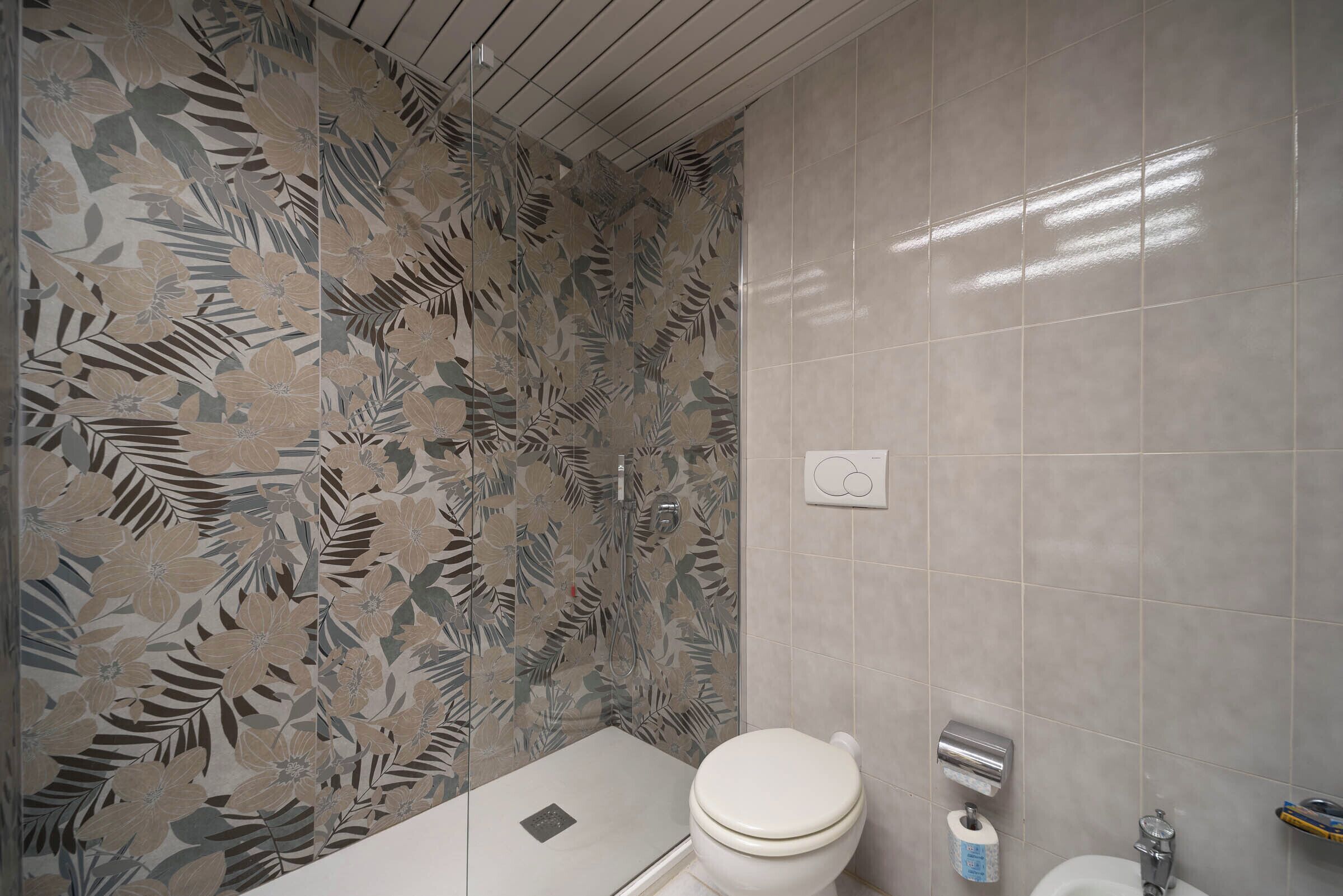 A bathroom with a toilet, a shower, and a sink.