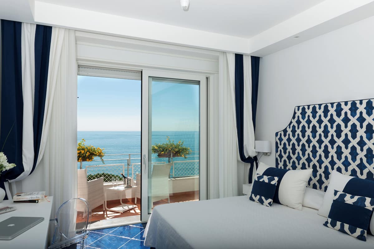 Ein Hotelzimmer mit Bett, Schreibtisch und Meerblick.