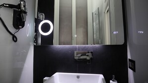 Een badkamer met een grote spiegel, een haardroger en een wastafel.