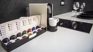Een koffieapparaat met een koffiepadsysteem, een witte mok en een tafel met een menukaart.