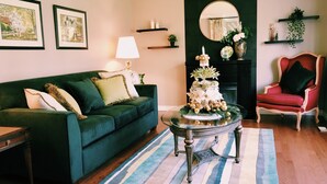 A living room with a green sofa, a round table with a vase, and a red chair.