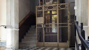 Eine prachtvolle Treppe führt zu einer Tür mit einem verzierten Metallgitter und einer runden Leuchte darüber.