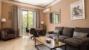 Ein Wohnzimmer mit einem braunen Sofa, einem Holztisch und einem Essbereich mit Tisch und Stühlen.