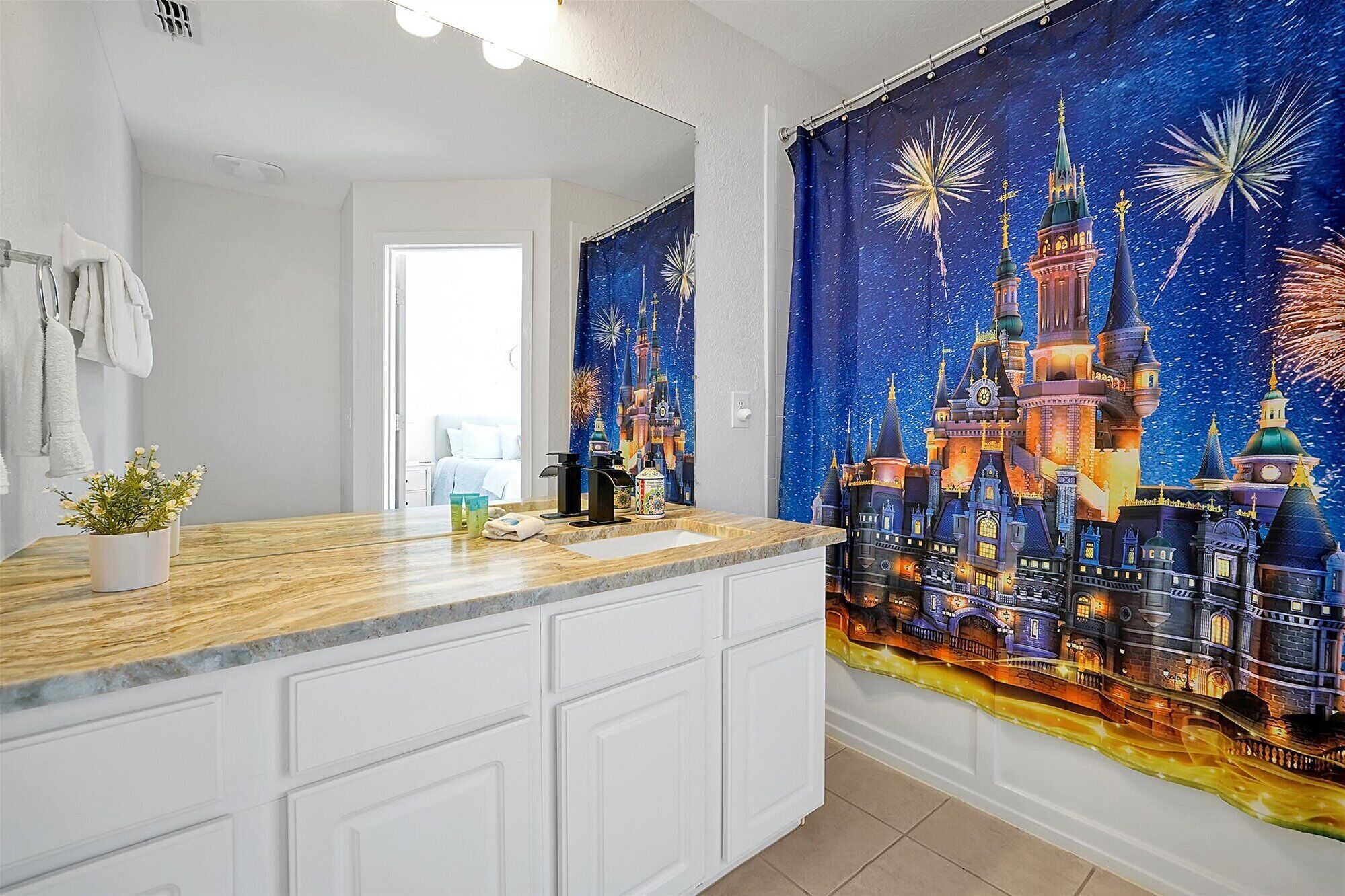 A bathroom with a large mirror, a wooden vanity, and a tapestry depicting a castle with fireworks.