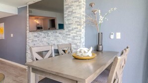 Et spiseområde med en væg i natursten, en vase med tørrede blomster og et moderne bord.