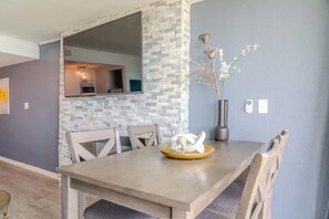 A dining area with a stone accent wall, a vase with dried flowers, and a modern table.