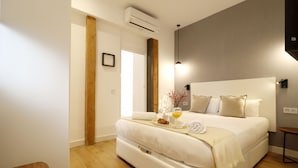A modern bedroom with a large bed, wooden beams, a bedside table, and a nightstand.