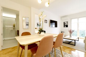 A modern dining area with a wooden table, cushioned chairs, and a vase with flowers.
