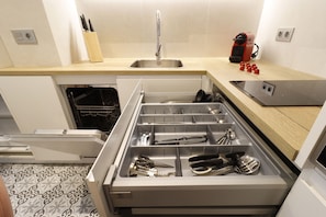 A modern kitchen with a stainless steel sink, a built-in oven, and a drawer organizer with utensils. - Royal Madrid (Madrid)