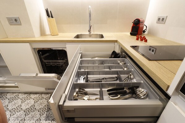 Eine moderne Küche mit Spüle aus Edelstahl, einem eingebauten Backofen und einem Schubladeneinsatz für Küchenutensilien.