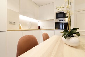 A modern kitchen with white cabinets, a wooden countertop, and a white vase with a plant.
