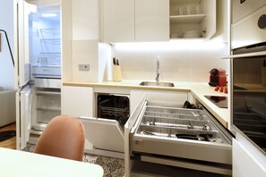Een kleine keuken met een ingebouwde vaatwasser, een spoelbak en een compacte oven.
