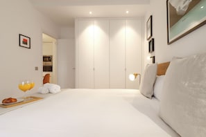 Een hotelkamer met een groot bed, een nachtkastje met een ontbijttafel, een wandlamp en een kledingkast.