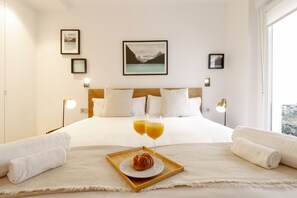 Ein Hotelzimmer mit einem großen Bett, einem Tablett mit Croissants und Orangensaft sowie Handtüchern.