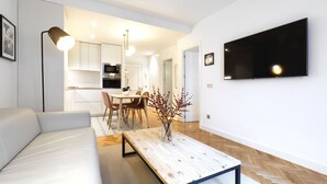 A modern living room with a sofa, a coffee table, and a TV mounted on the wall.