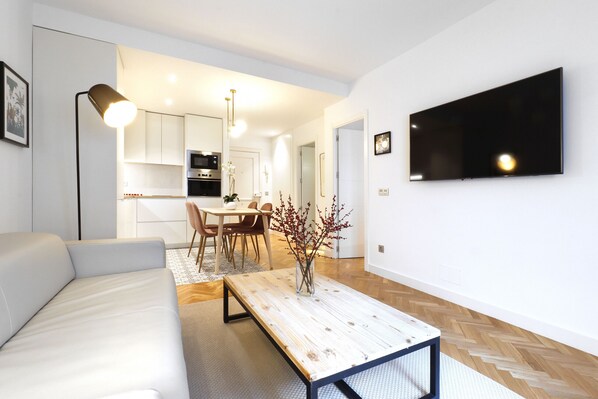 A modern living room with a sofa, a coffee table, and a TV mounted on the wall.