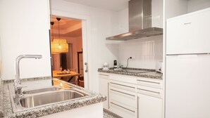 A modern kitchen with white cabinetry, a stainless steel sink, a built-in stove, and a stainless steel range hood. - Casa Centro Torrevieja San Policarpo (Torrevieja)