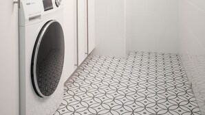 A hotel bathroom with a washing machine, a shower, and patterned floor tiles. - Casa Centro Torrevieja San Policarpo (Torrevieja)