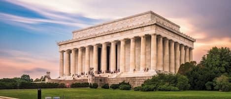 A large neoclassical building with a prominent front facade, columns, and steps leading up to an entrance.