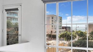 Quarto com uma grande janela que oferece vista para uma paisagem urbana e um corpo d'água.
