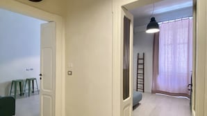 Ein geräumiger Raum mit Holzboden, einer Tür zu einem anderen Raum, einer Hängeleuchte und einem kleinen Tisch mit Hocker.