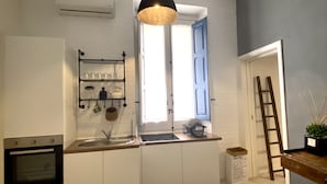 Eine moderne Küche mit weißen Schränken, einem Einbauofen, einer Spüle und einer Pendelleuchte.
