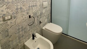 Ein Badezimmer mit gemusterten Fliesen, einem Bidet und einer Toilette.