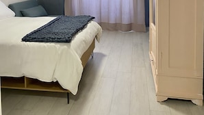 Ein Schlafzimmer mit Bett, Schrank, Pendelleuchte und einem Vorhangfenster.