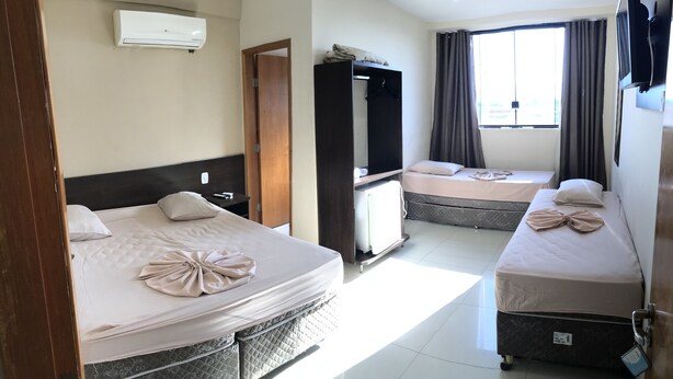 Habitación de hotel con dos camas, un armario, un televisor y una ventana con cortinas.
