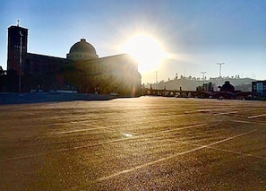Un estacionamiento con un gran edificio al fondo, que incluye una cúpula y una torre.