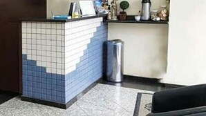 Una zona de recepción con mostrador de baldosas, un cesto de basura y una máquina de café.