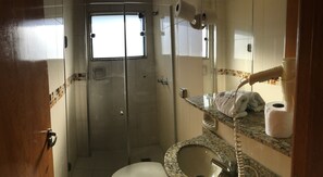 Un baño con ducha, inodoro, lavabo y toallero.