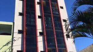 Un edificio alto con diseño moderno, que presenta grandes ventanales y un detalle rojo en la fachada.