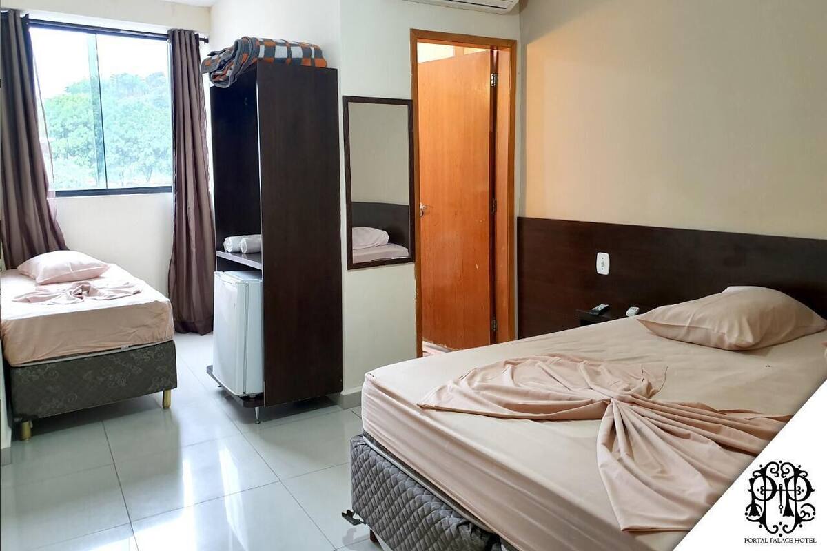 Una habitación de hotel con dos camas, un armario, un escritorio pequeño y un equipo de aire acondicionado.