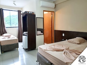 Una habitación de hotel con dos camas, un armario, un escritorio pequeño y un equipo de aire acondicionado.